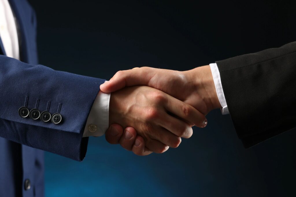 Business partners shaking hands on dark blue background, closeup